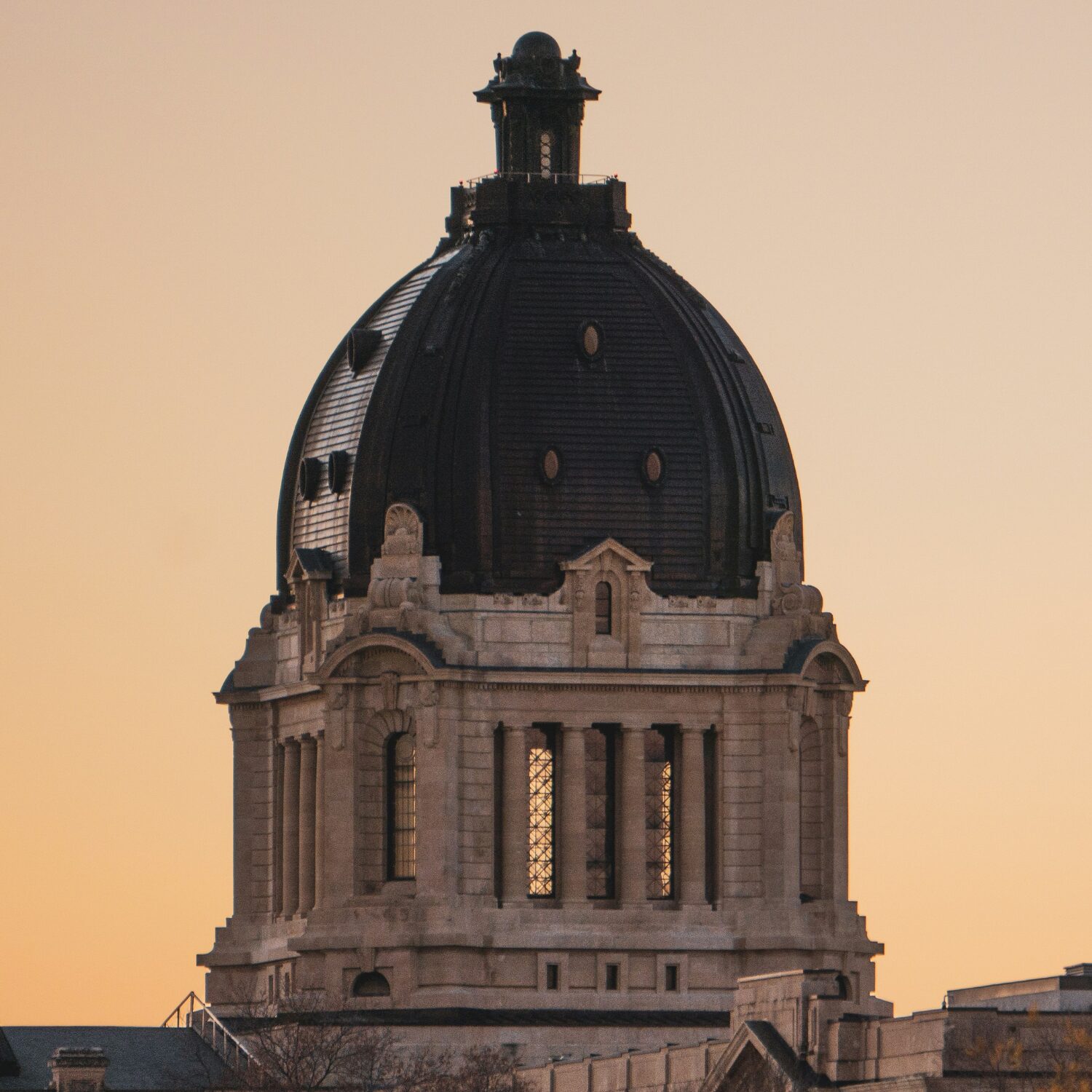 Legislative building in Regina, Saskatchewan with a copper dome at the top, and a purple sunset in the background.