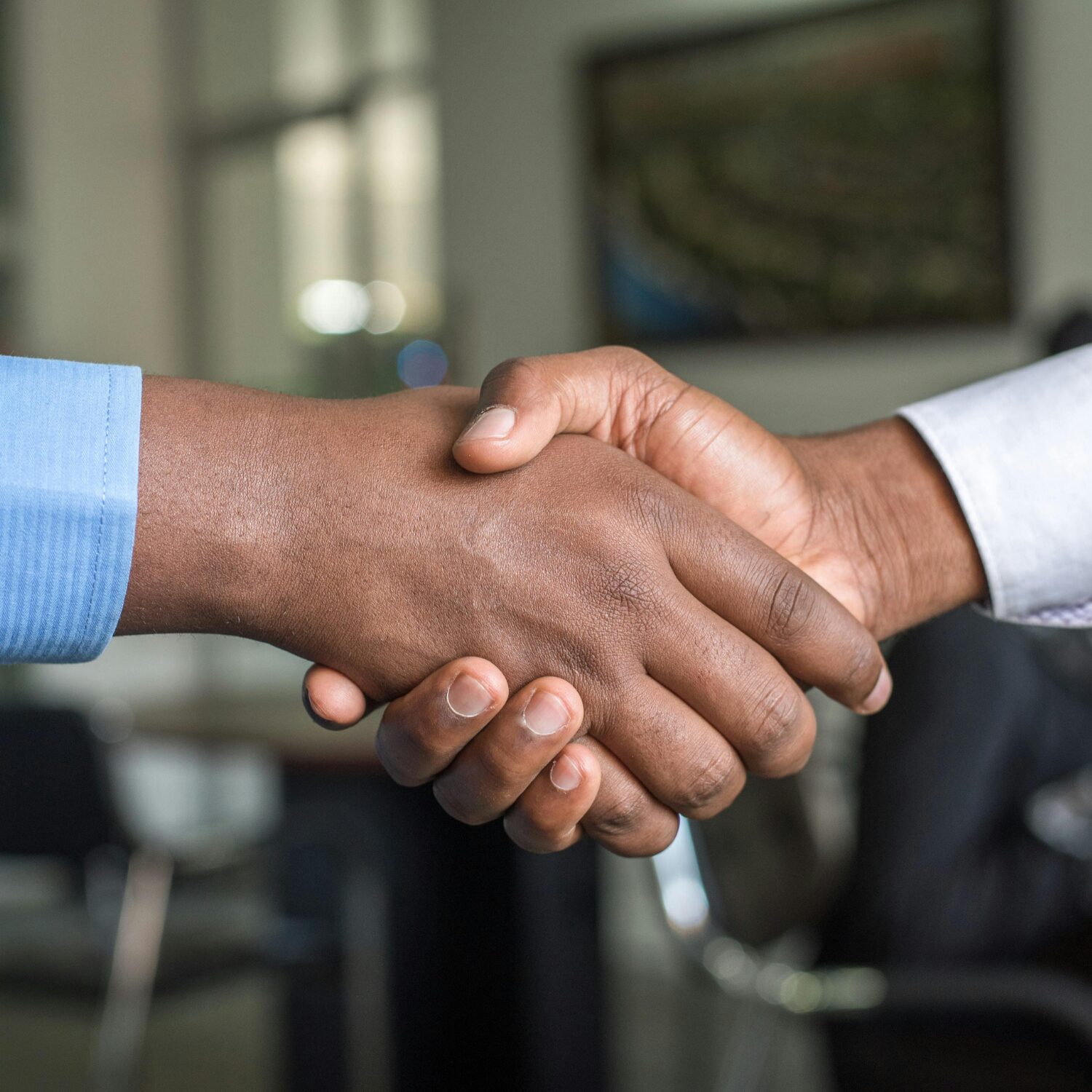 Two Black individuals shaking hands, it is a close-up of their hands.