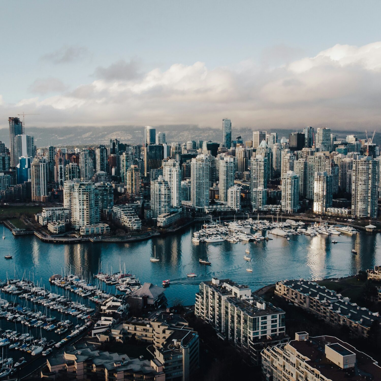 Vancouver's skyline in front of a body of water with boats in it. The sky is a gray colour.
