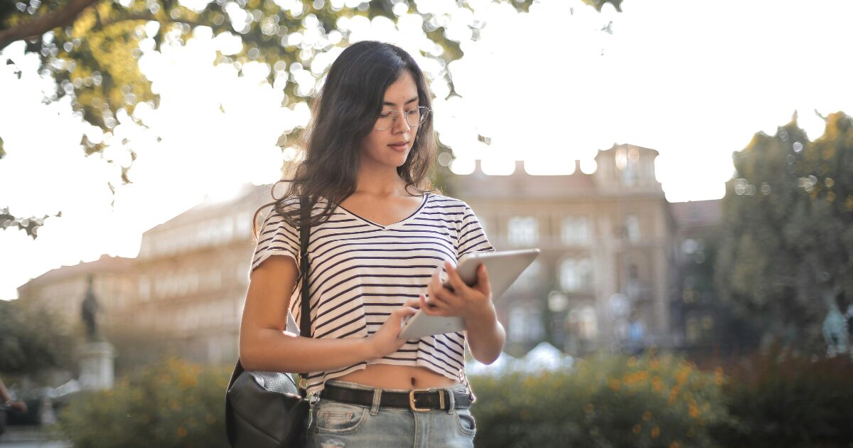A Caucasian woman wearing a black and white stripe top using her tablet.