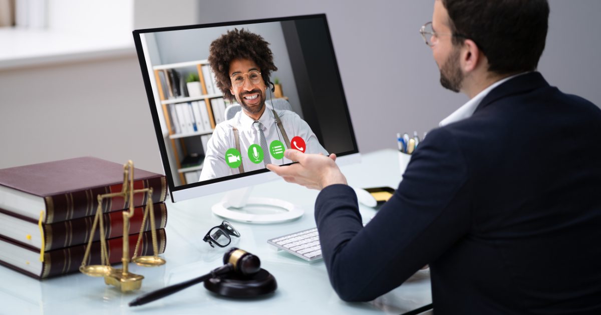 Lawyer on video call with client on large monitor in an office