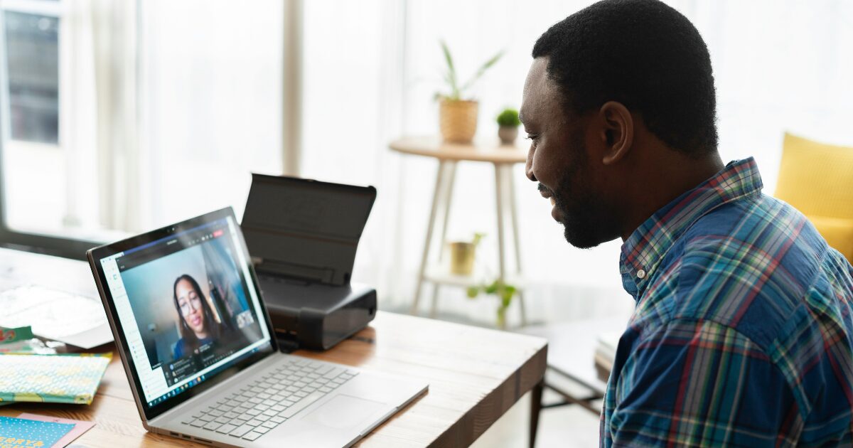 A man in a plaid shirt on a video call to get a document drafted by an expert.