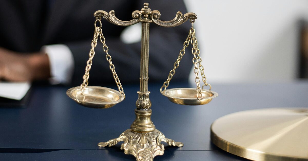 Gold coloured scales of justice on a blue table.