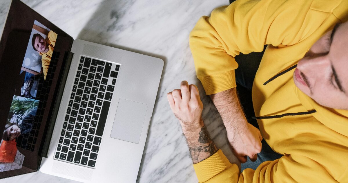 A young Caucasian man on a video notary appointment, wearing a yellow sweater.