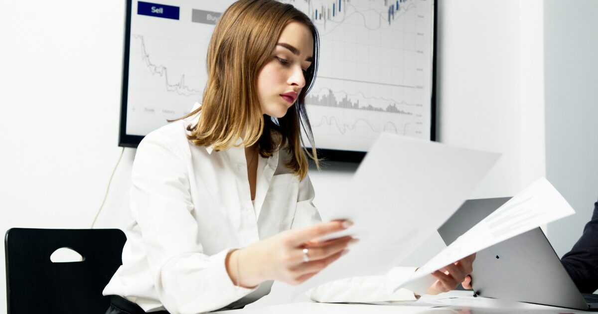 298 A Caucasian woman wearing a white long-sleeved blouse reading documents