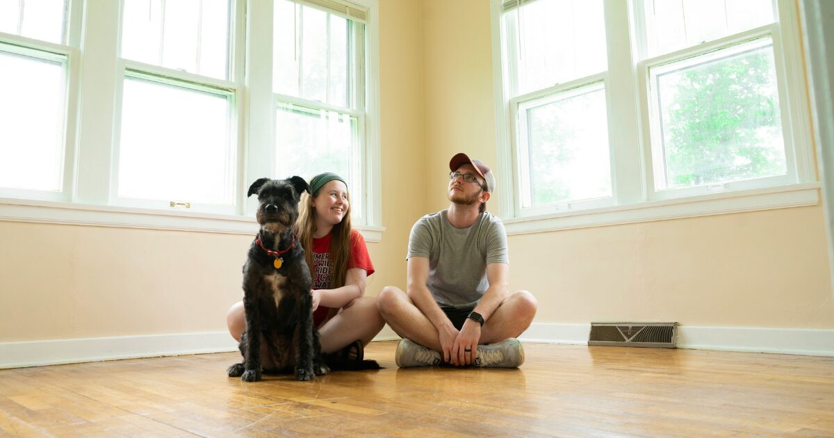 314 A Caucasian man and woman sitting on the floor with their black dog.