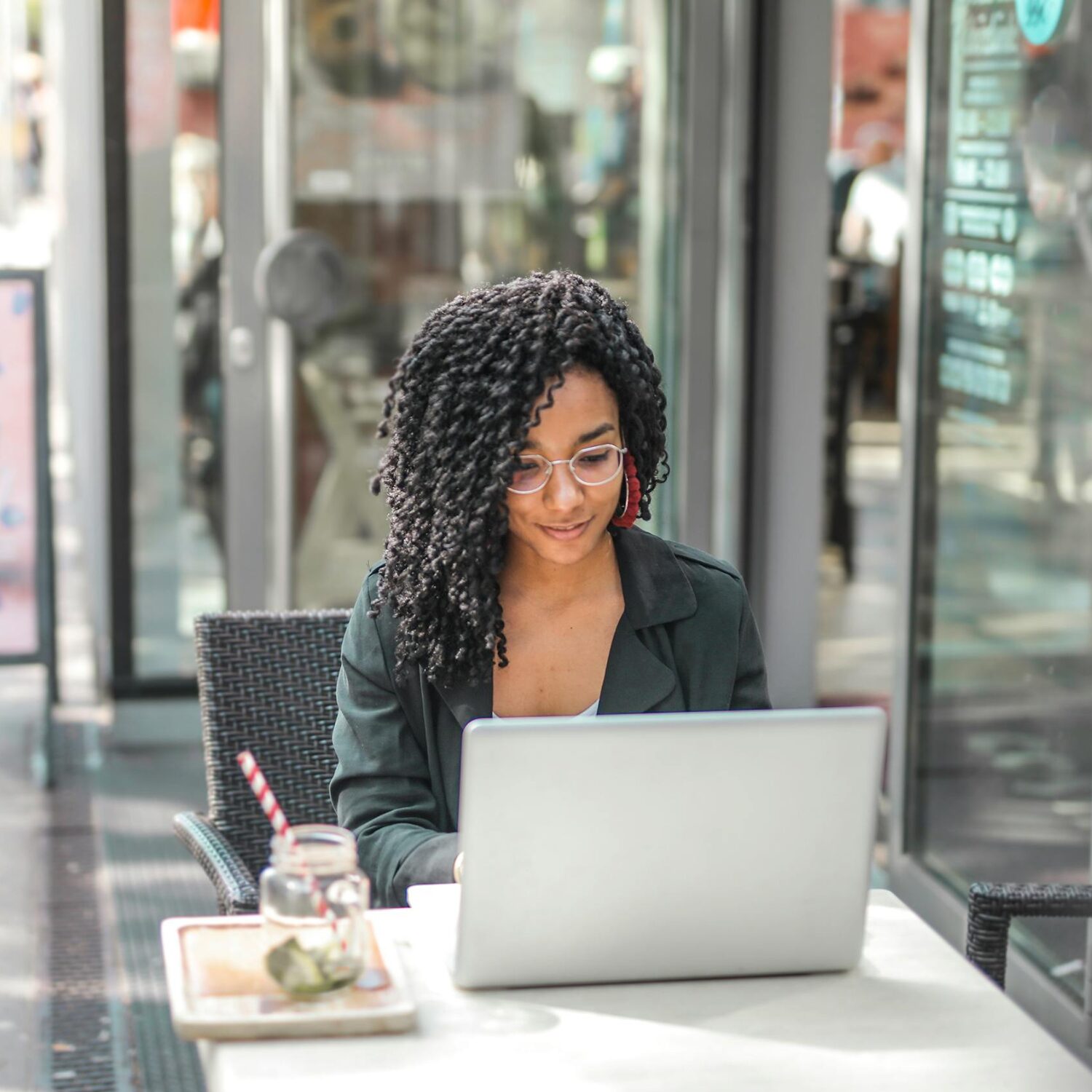 A Black woman wearing a black blazer smiling while in front of her laptop