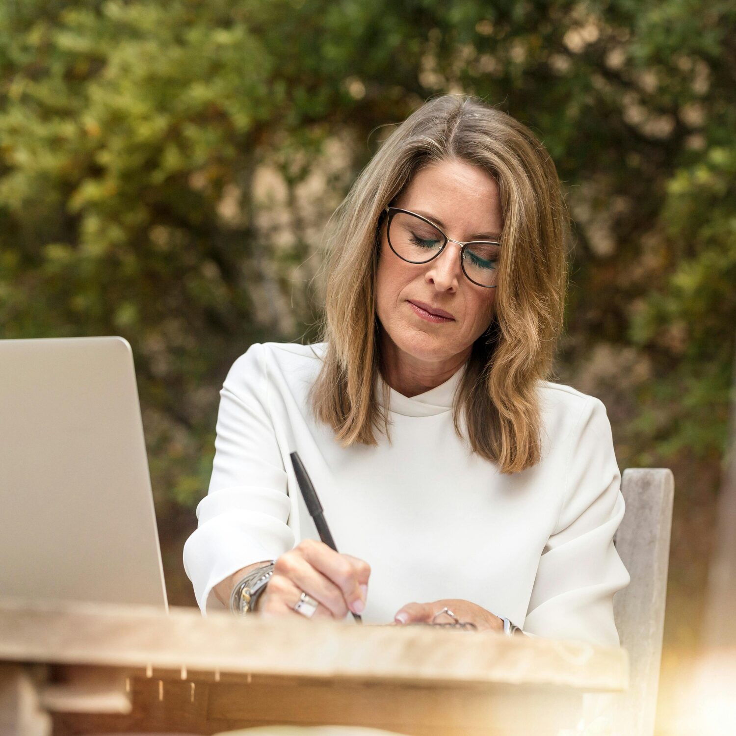 A Caucasian woman wearing a white blouse writing something down