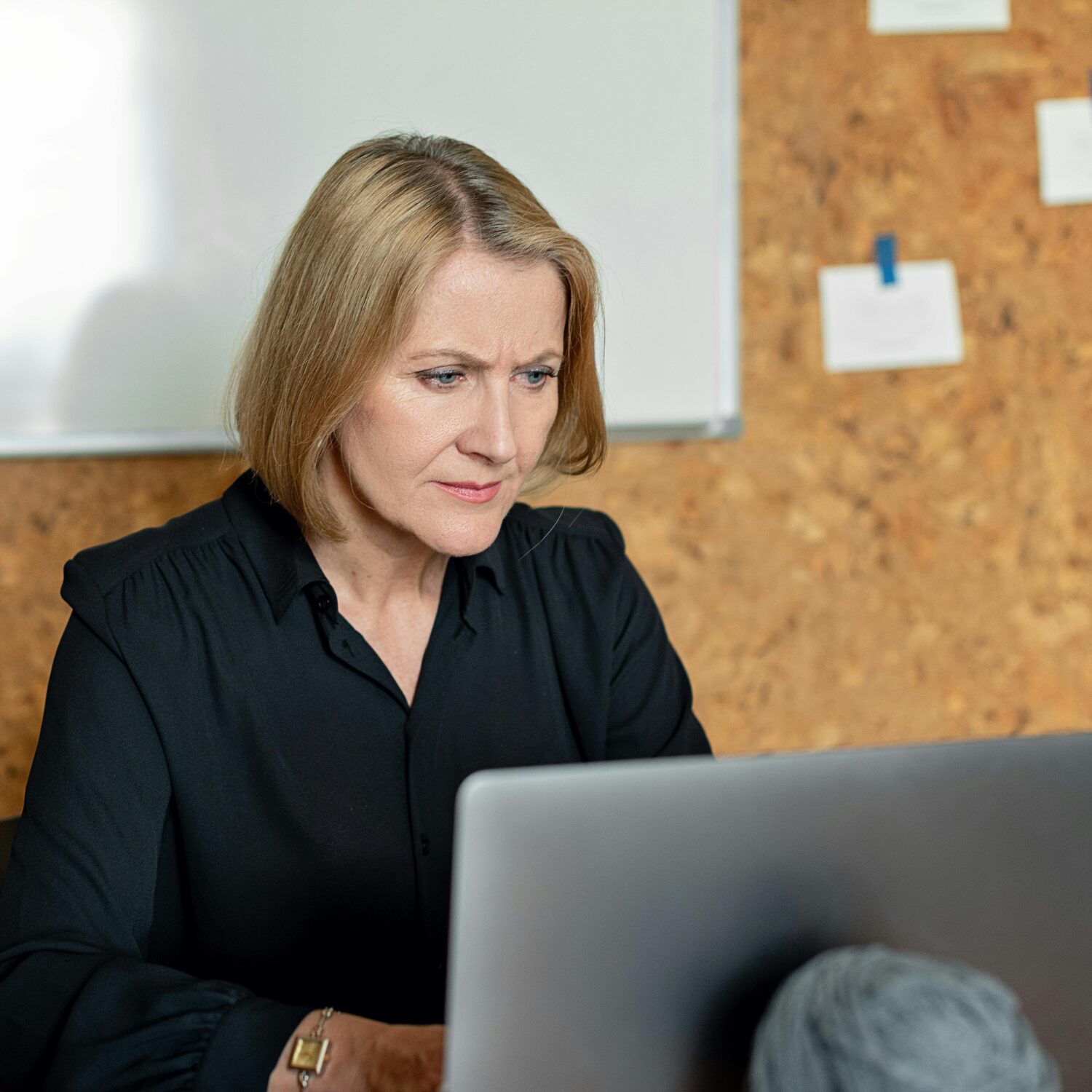 A Caucasian woman wearing a black long sleeve shirt is using a laptop.