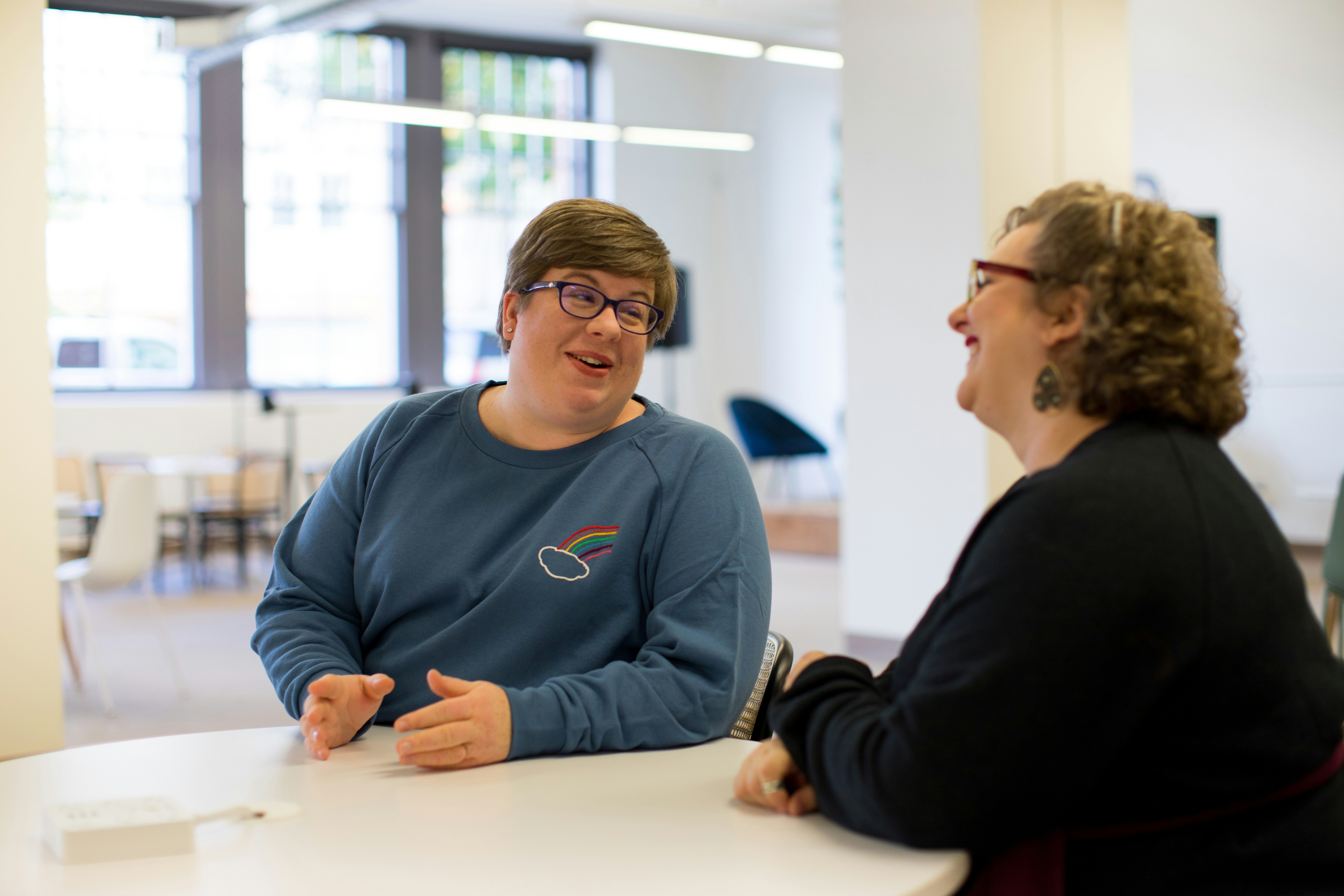 Group of plus size employees in bright, modern, open office in rainbow sweater