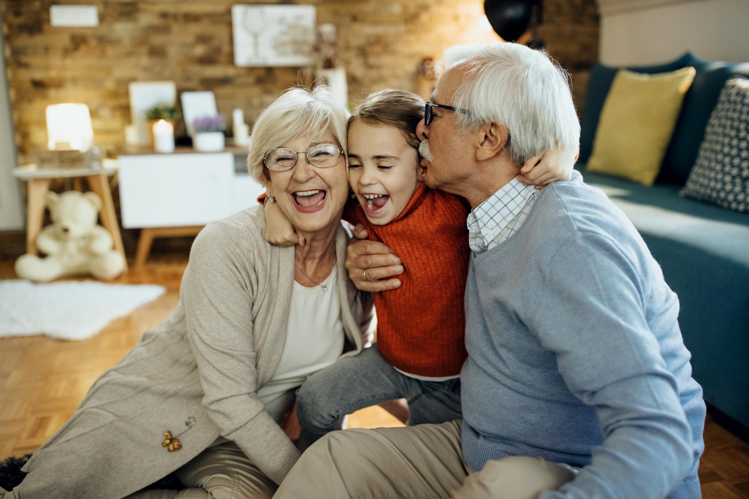 Grandparents with their grandchild sitting down smiling and laughing