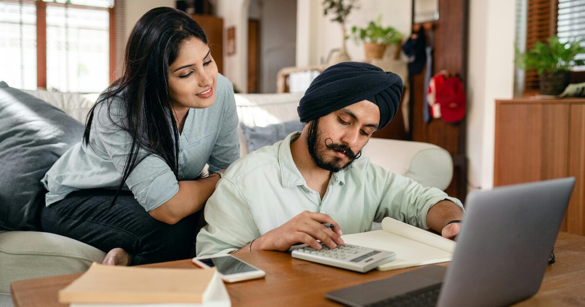 In-Blog-Thumbnails-44 An Indian man and an Indian woman working on paperwork together, sitting at a coffee table.