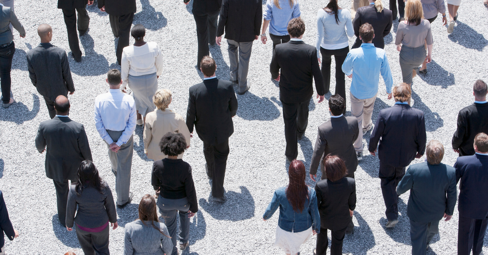 A diverse group of professionals in business attire walk together outdoors, viewed from above.